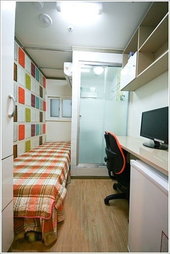 色とりどりの壁が印象的な部屋の画像です。部屋の中央にベッドが置かれ、その横にはデスクとチェアがあります。全体的にモダンな雰囲気の部屋ですね。