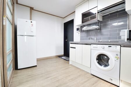 白を基調としたキッチンと洗濯機・冷蔵庫が設置された明るい生活空間