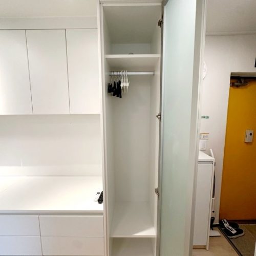 収納空間、衣類を掛けるハンガー、洗濯機があるシンプルな部屋の画像です。