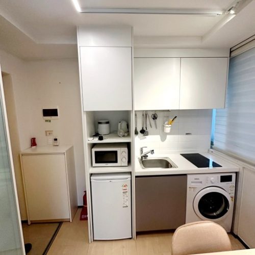 画像は簡単なキッチンルームを示しています。冷蔵庫、電子レンジ、洗濯機などの家電製品が配置されています。清潔で整理されたキッチンで、効率的に使えそうです。