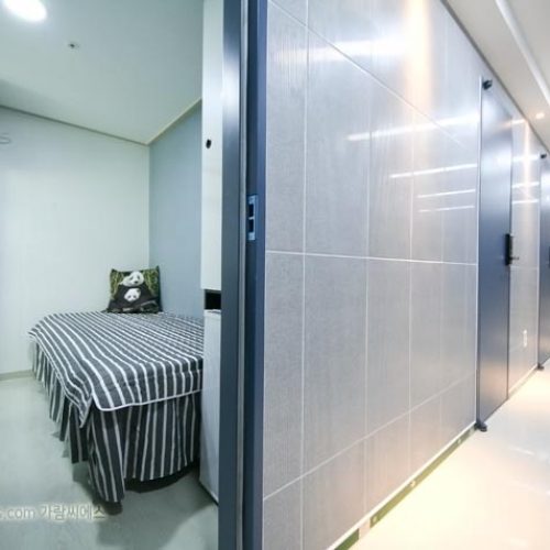 清潔感あふれる、白とブルーでデザインされた個室のベッドルーム。