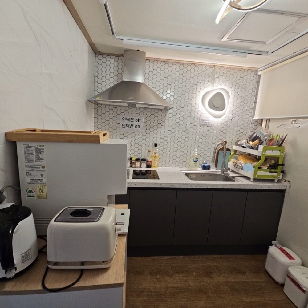 部屋の中にある様々な家電製品や台所用品を確認できる写真です。 キッチンは六角形のタイルで装飾されており、洗濯機や調理器具などが設置されています。ほとんどの部品は韓国語で表示されています。